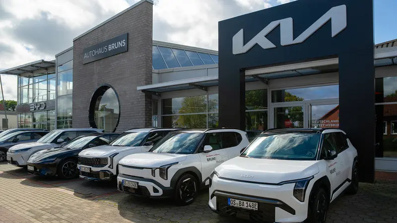 Außenansicht unserers Autohauses mit den Marken Kia und BYD, davor stehen mehrere neue Autos in einer Reihe auf dem Parkplatz.